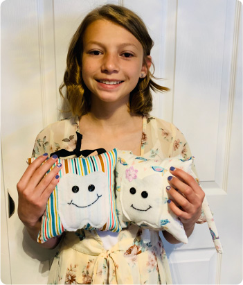 Hannah Forster holding two Tooth Fairy Pillows