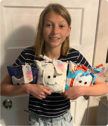 Hannah Forster holding three tooth fairy pillows available for purchase